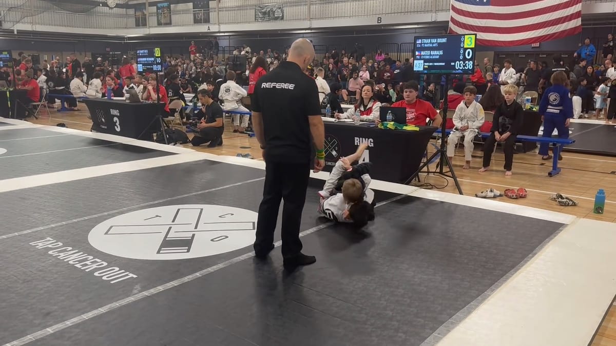 Ethan and Mateo Nanalig grappling on the Ring 4 mat during the final, the referee watching