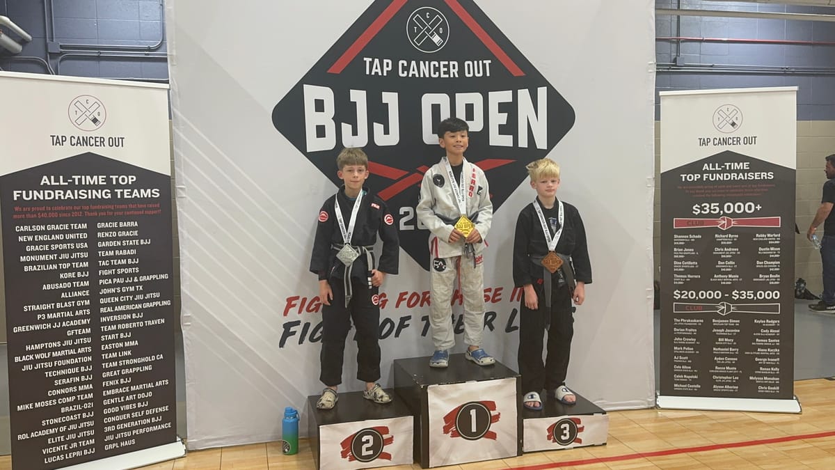 Ethan on the second-place step of the podium with his silver medal, beside the gold and bronze winners